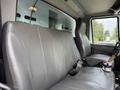 The interior of a 2012 International TerraStar showing a spacious gray vinyl bench seat with a seatbelt and a gear shift visible in front