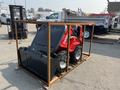 A red 2025 AGT Industrial SDA-140W(Z) compact loader is secured in a metal frame with a black front bucket attached