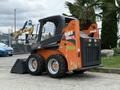 A 2017 Gehl R105 skid steer loader with an orange and black exterior features four wheels a bucket attachment and a protective cage around the operator area