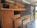 Interior view of a 2008 Workhorse W62 featuring wooden cabinetry workstations with various storage compartments and equipment for operational use