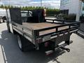 A 2016 Ford F-550 flatbed truck with a wooden bed and protective back panel view from the rear angle