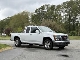 A white 2012 GMC Canyon pickup truck is parked with its cab and bed clearly visible showcasing silver wheels and chrome accents