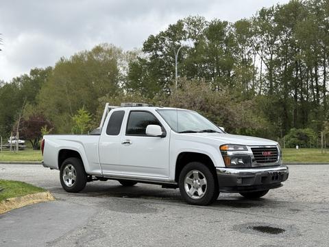 A white 2012 GMC Canyon pickup truck is parked with its cab and bed clearly visible showcasing silver wheels and chrome accents