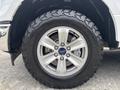 Close-up of a silver alloy wheel with a black off-road tire featuring the Ford logo in the center of the wheel