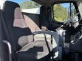 Interior of a 2006 Freightliner M2 106 featuring two fabric seats with a center console and storage compartments between them