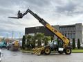 A 2014 Caterpillar TL1055C telehandler with an extended boom and fork attachment facing upward
