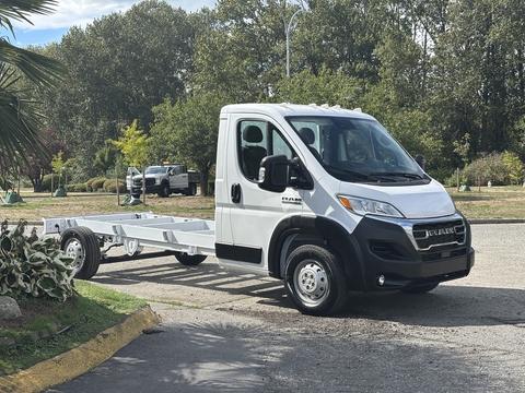 A 2023 RAM Promaster 3500 chassis cab in white with a low profile and open truck bed design parked on a driveway