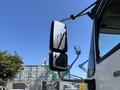 A side mirror of a 2011 International 4300 truck reflecting a clear sky and displaying water droplets on its surface