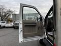 A 2009 Ford F-550 with the driver's side door open displaying a beige interior door panel with a handle and storage compartment