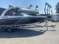 A 2013 Larson 238 boat on a trailer with a sleek black hull and white accents  The boat has a covered cockpit area and is labeled with the name Disappearing Act III