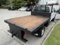 A 2015 Ford F-350 SD with a flatbed design featuring a wooden surface and a black metal frame without a tailgate