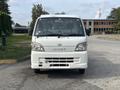 A 2010 Daihatsu Hijet van facing forward with a white exterior and large windshield showcasing a simple design and functional front features