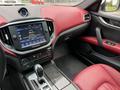 Interior of a 2016 Maserati Ghibli featuring a touchscreen display dashboard with red leather seats and a gear shift in the center console