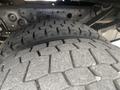Close-up of a large tire from a 2003 Ford F-450 SD showcasing deep tread patterns and robust rubber construction