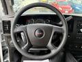 Steering wheel of a 2023 GMC Savana with the GMC logo on the center and dashboard displays behind it