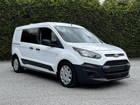 A white 2016 Ford Transit Connect with a sleek design and large side windows, featuring a black front grille and hubcap wheels
