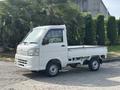 A white 2010 Daihatsu Hijet mini truck with a flatbed and compact design parked at an angle