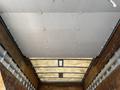 The interior of a truck bed featuring a flat ceiling with metal hooks for securing cargo and wooden walls for structural support