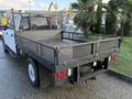 A 2020 Ford F-350 with a flatbed truck bed featuring a metal mesh railing and a spare tire mounted on the rear