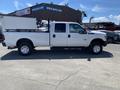 A white 2016 Ford F-350 Super Duty with a flatbed truck body and extended cab is shown from the side