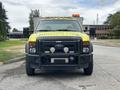 Front view of a 2010 Ford F-550 Super Duty vehicle with a bright yellow body and an orange light bar on top featuring a black grille and heavy-duty front bumper