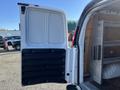 A white 2016 GMC Savana van with an open back door revealing a spacious cargo area and black rubberized door panel details