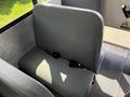 A gray, padded bus seat with seatbelts attached, part of the interior of a 2011 Freightliner B2