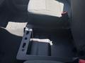 A center console storage compartment in a 2023 Ford F-350 SD with a textured black surface and two slots for accessories