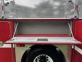 A 2002 GMC C7500 fire truck with a red and silver design featuring a drop-down storage compartment made of metal with a perforated surface
