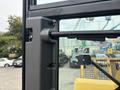 Close-up of the cab door mechanism of a 2012 Caterpillar 980 showing the handle and window frame