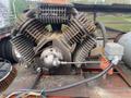 A 2000 Baldor Air compressor with a large, rugged metal body featuring multiple prominent cooling fins and an intricate arrangement of hoses and connectors