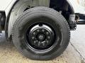 A close-up view of a black tire mounted on a 2015 Freightliner M2 truck with chrome wheel bolts and a metallic hub assembly