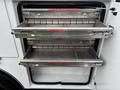 A utility storage compartment with two slide-out metal drawers labeled for tools and supplies