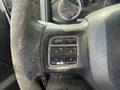 Close-up of a steering wheel control panel featuring buttons for phone and cruise control in a 2016 RAM 5500 with a worn texture on the steering wheel surface