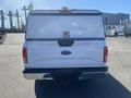 A white 2017 Ford F-150 truck with a covered bed and a Ford emblem on the tailgate