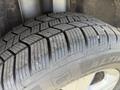 A close-up of a winter tire on a 2014 Ford Escape showing detailed tread patterns and sidewall markings