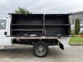 A 2016 Ford F-550 Super Duty truck with an open flatbed and large black storage compartments on the sides