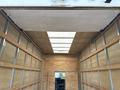 Interior view of a 2024 Ford E-450 box truck featuring wooden paneling and a flat ceiling with metal supports