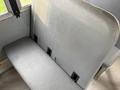 A grey bus seat with a textured surface and attachment clips visible on the backrest
