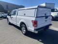 A white 2017 Ford F-150 with a cap on the bed parked in a vehicle lot angled to the right