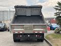 A 2014 Ford F-550 dump truck viewed from the rear with its bed raised and a black liner visible inside the truck bed