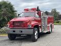 A red 2002 GMC C7500 fire truck with a ladder and hose compartments visible on the side and emergency lights on top