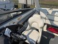 A 2013 Larson 238 interior featuring a white driver's seat and steering wheel with a console displaying controls and a sound system