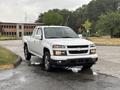 A white 2011 Chevrolet Colorado pickup truck is parked with its front slightly angled towards the viewer showcasing its distinctive grille and headlights
