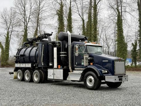 A 2018 Kenworth T800 vacuum truck with a black tank and multiple hoses mounted on the chassis, featuring a prominent front grille and side mirrors