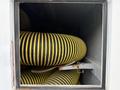 A black and yellow striped heavy-duty hose coiled inside a compartment of a 2014 International TerraStar vehicle