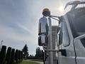 A 2013 International WorkStar featuring a shiny chrome exhaust stack and a reflective side mirror with an amber safety light