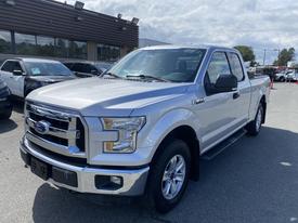 A 2015 Ford F-150 in silver with a double cab design featuring chrome accents and a large front grille