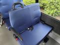 A blue upholstered seat from a 2020 Chevrolet Express with an armrest and seatbelt attached