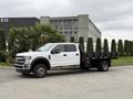 A 2020 Ford F-550 truck with a flatbed design in white color parked on a concrete surface